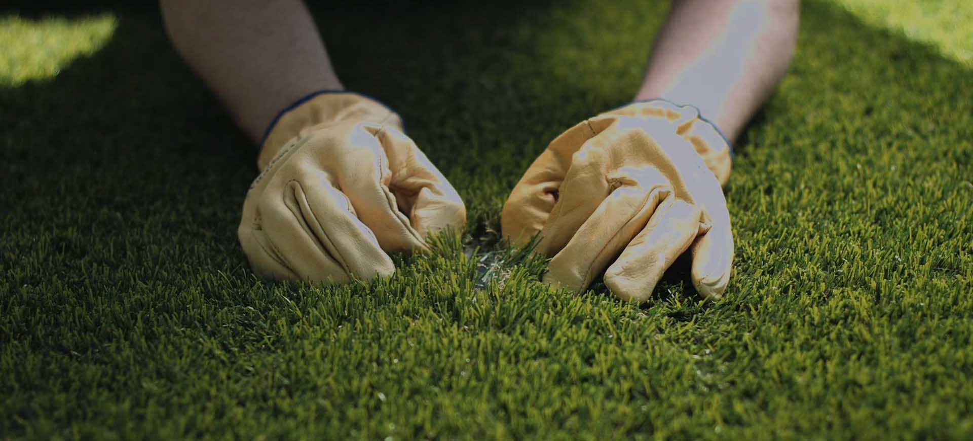 uma pessoa colocando as mãos com luva em um campo de grama artificial